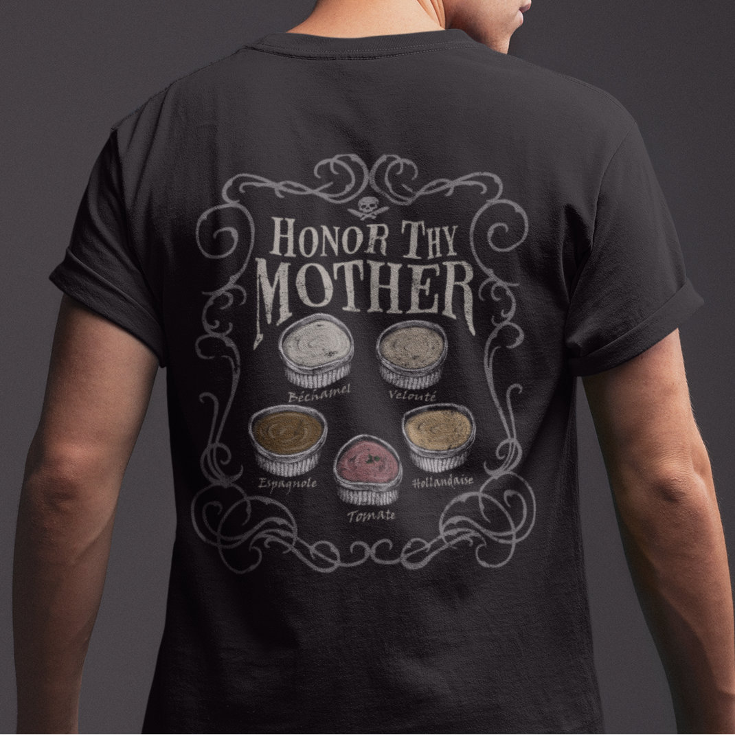A man shown from the back wearing a black t-shirt with a detailed graphic on the back that reads 'HONOR THY MOTHER' above six circular illustrations, set against a dark gray studio background.