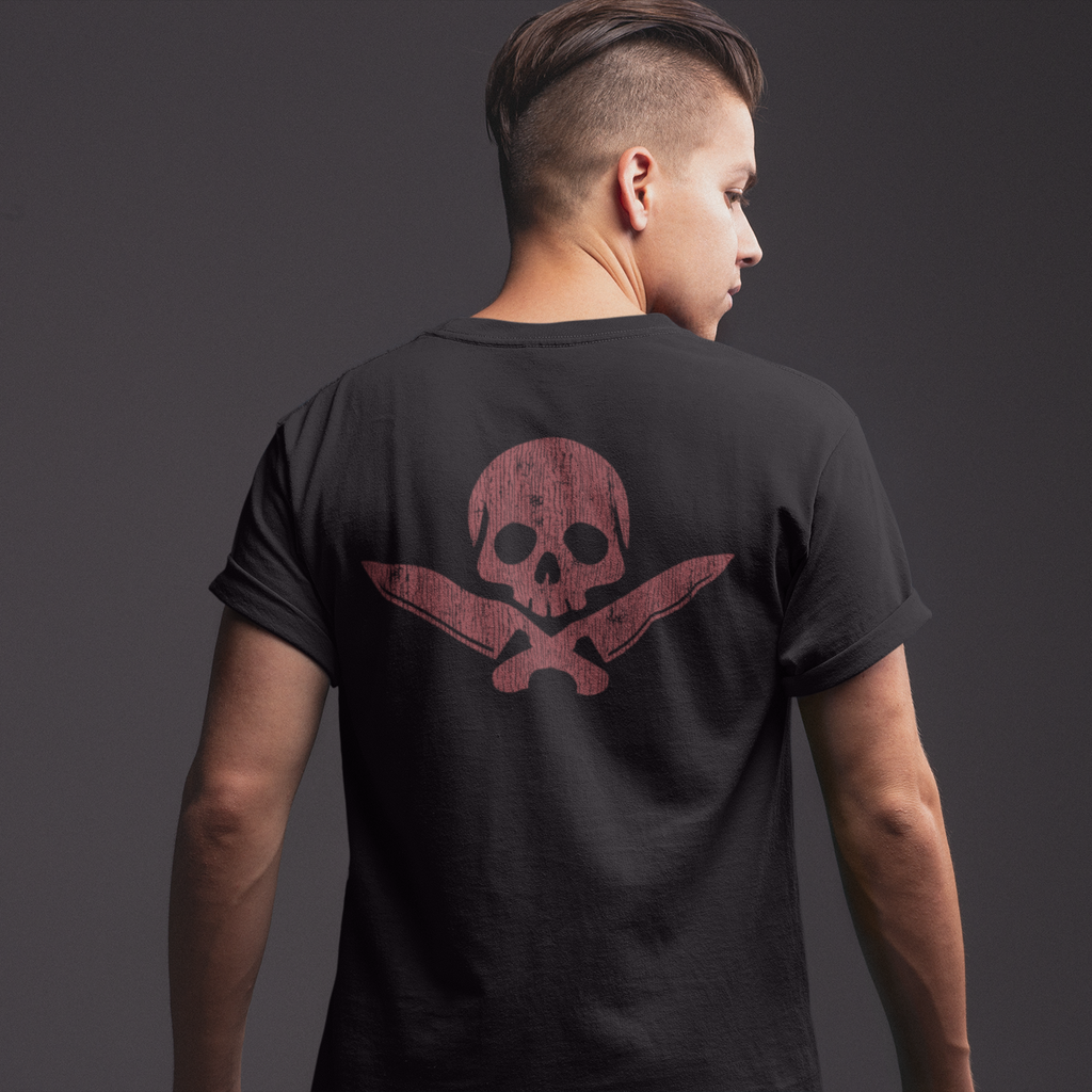 Person wearing a black t-shirt with a red skull and crossbones design on the back against a dark background