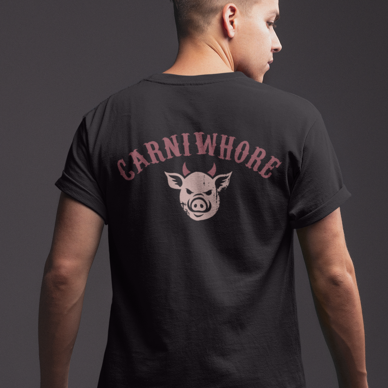 Person wearing a black t-shirt with 'Carniwhore' logo on the back against a dark background