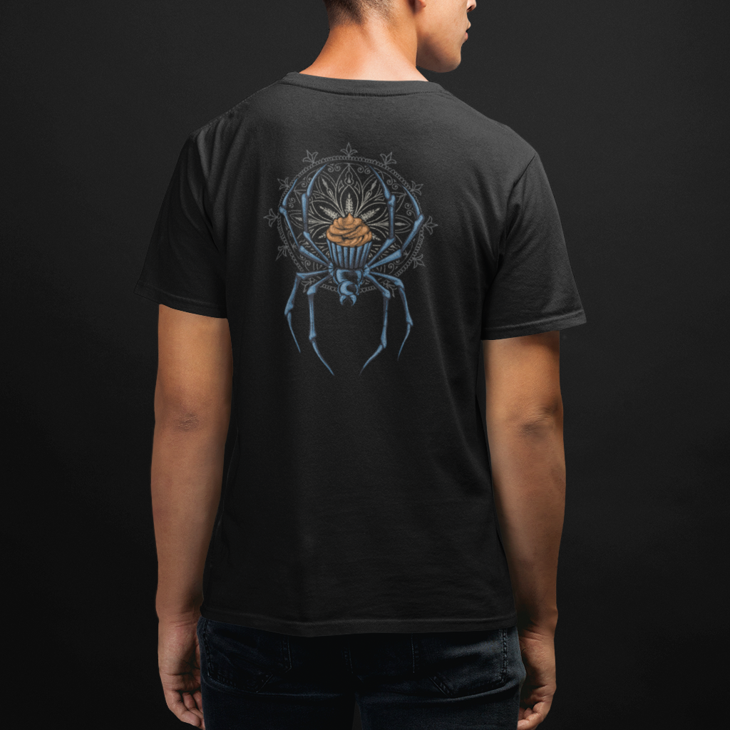 A man viewed from the back wearing a black t-shirt with a detailed graphic of a spider and a golden sun on the back, set against a dark studio background.