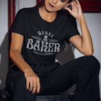 Woman wearing a black t-shirt with 'Rebel Baker' text, sitting indoors.