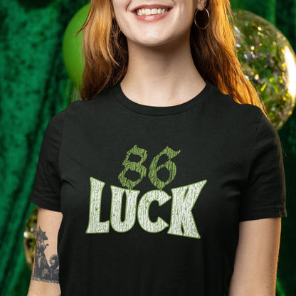 Person wearing a black t-shirt with '86 Luck' design against a green background