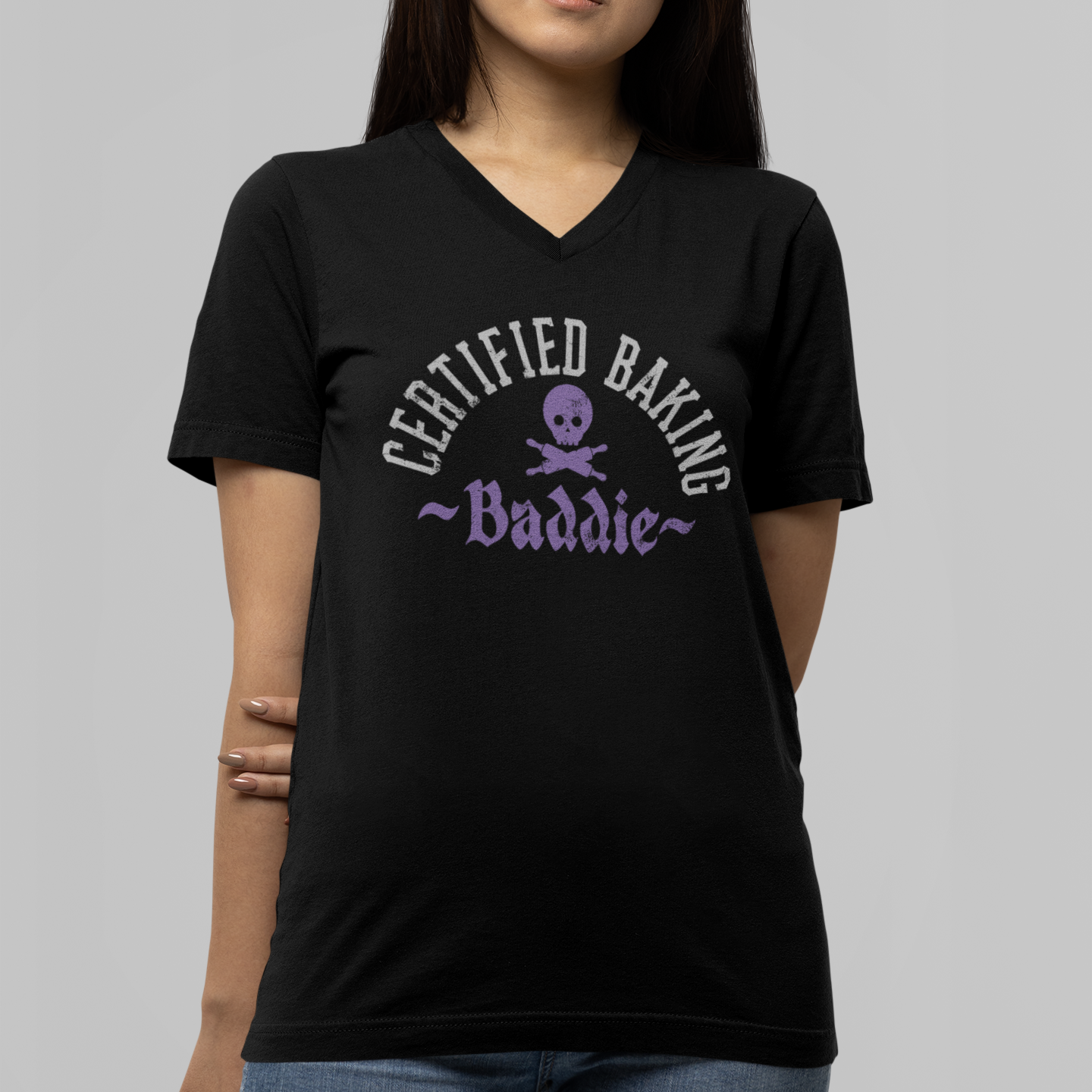 Person wearing a black t-shirt with 'Certified Baking Baddie' text and skull design on a gray background