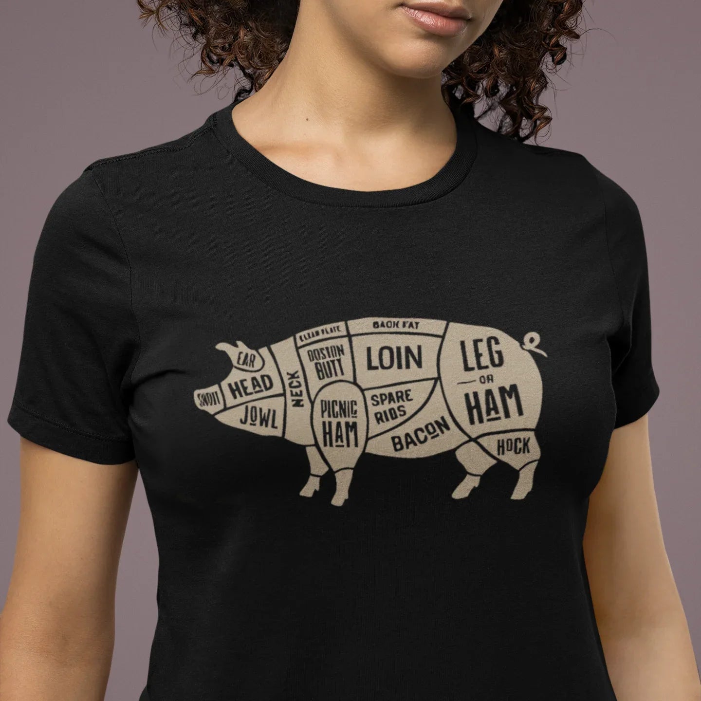 Person wearing a black t-shirt with a pig diagram and text on a plain background