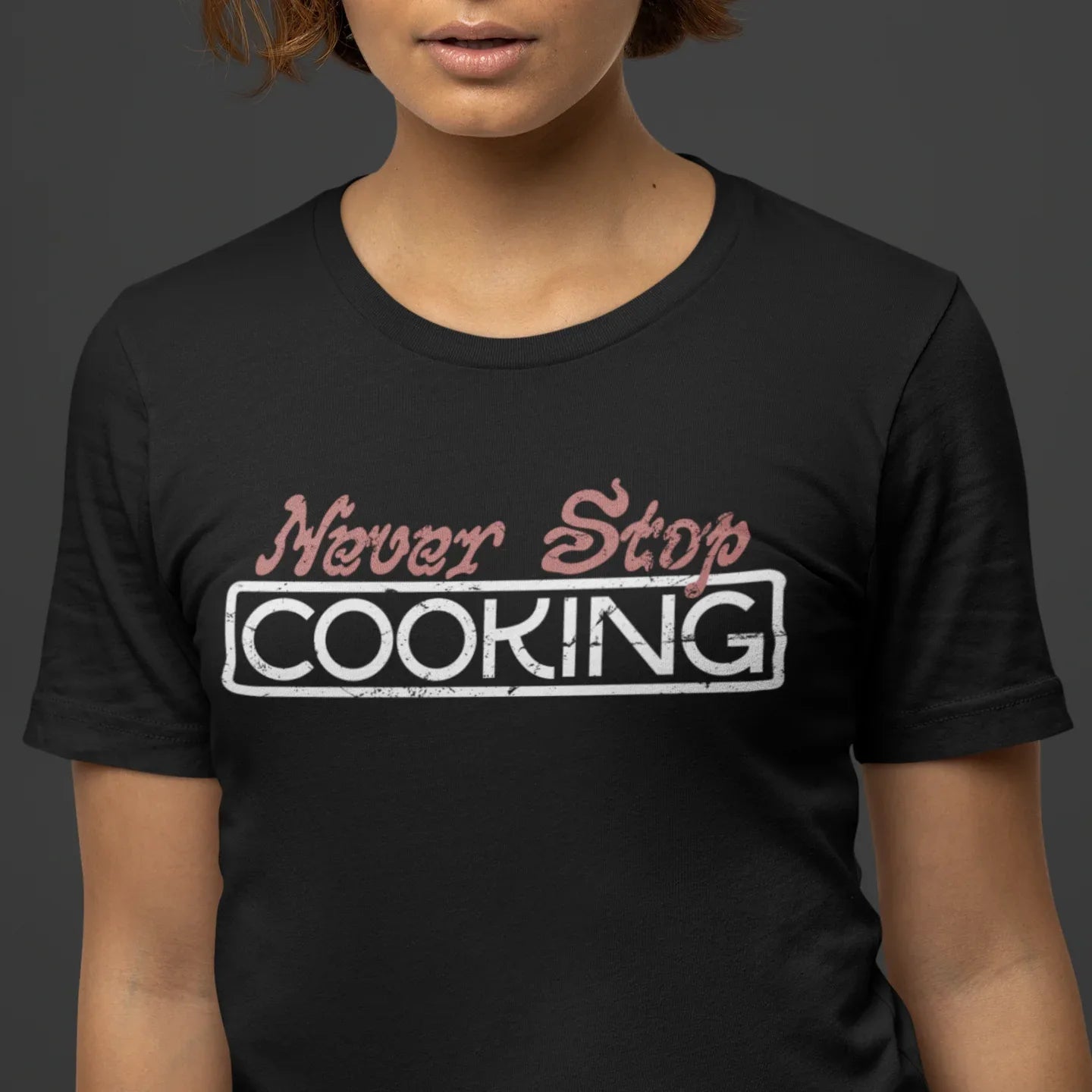 Person wearing a black t-shirt with 'Never Stop Cooking' text design.
