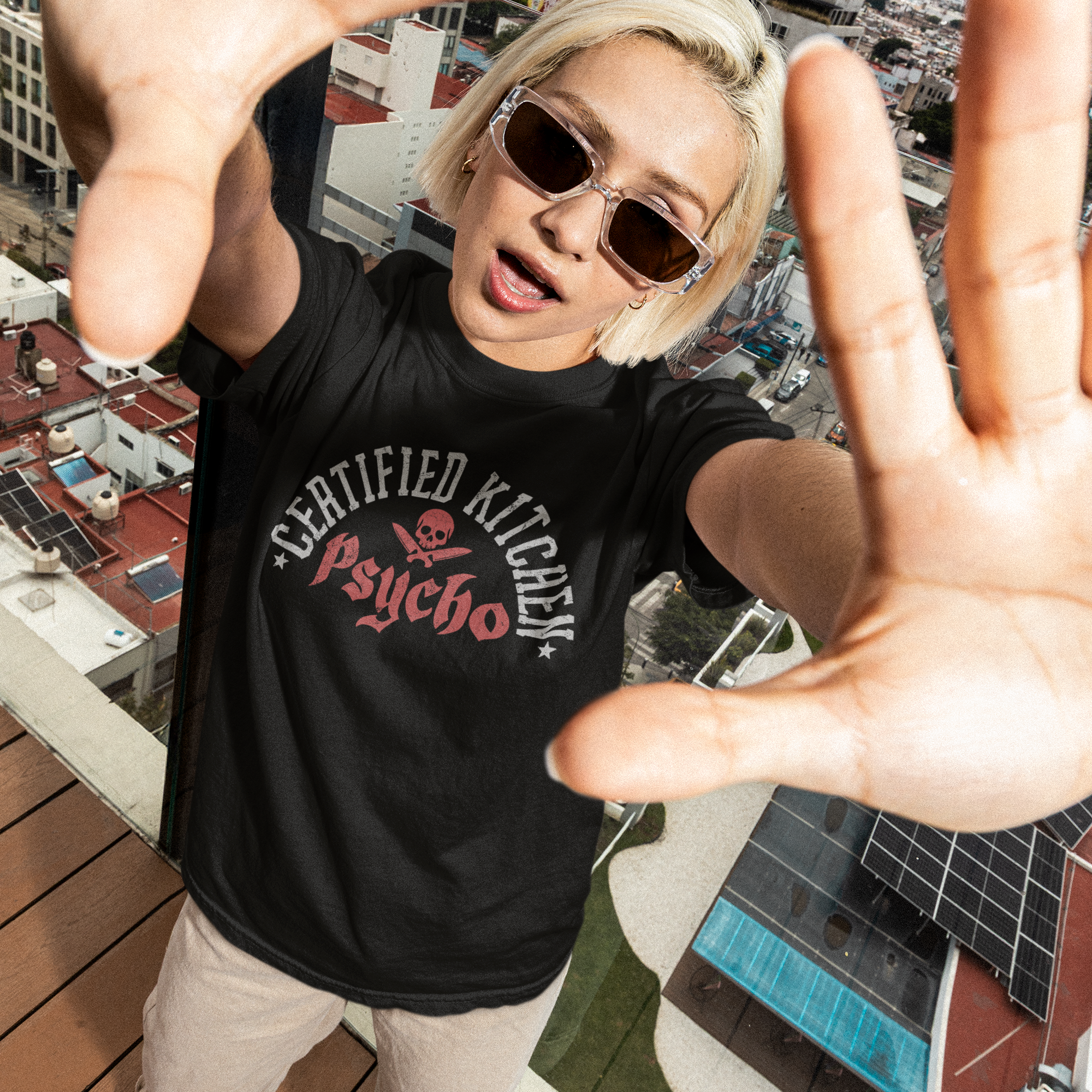 Person wearing a black t-shirt with text and graphics, standing on a rooftop with cityscape in the background.