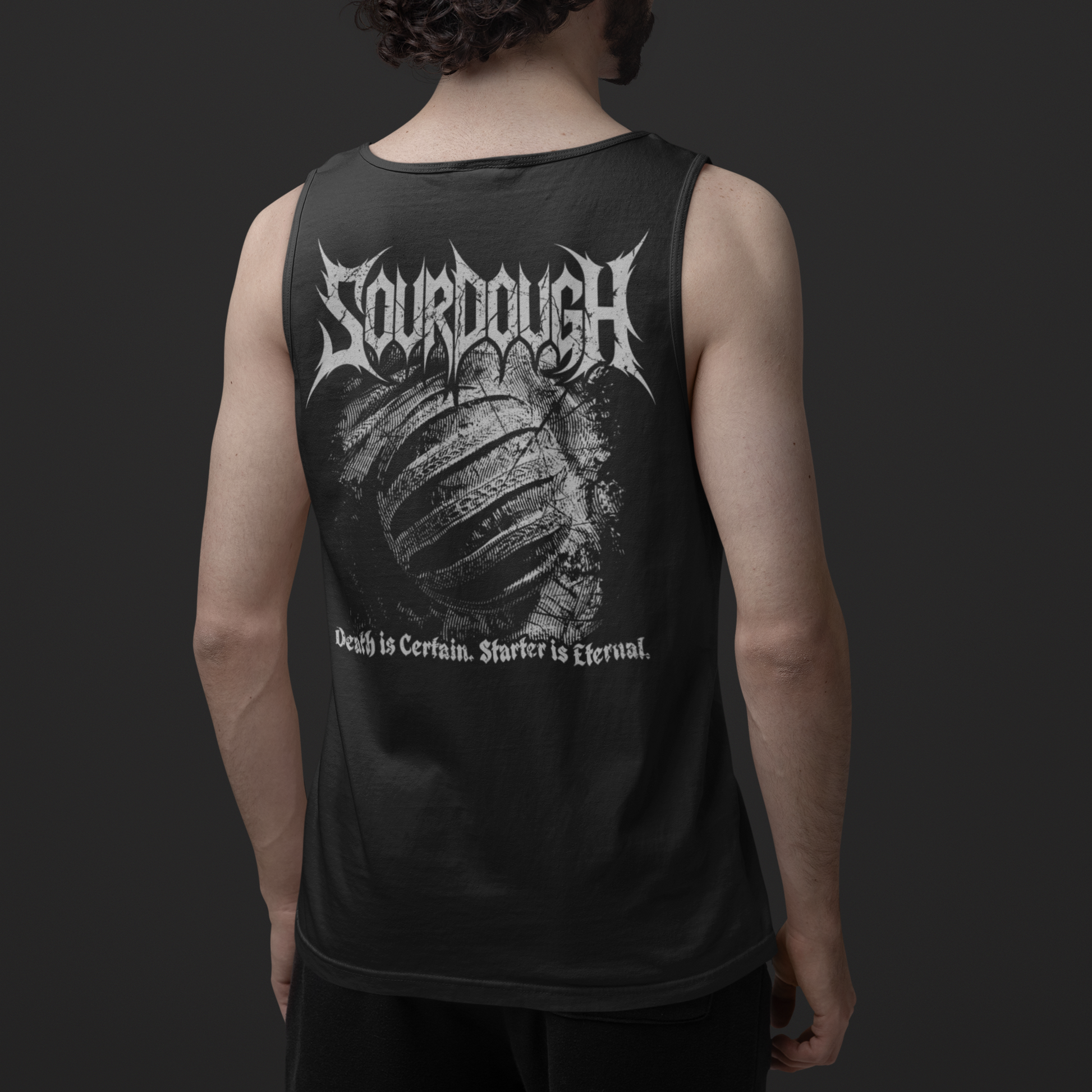 A man viewed from behind wearing a black sleeveless tank top with a large white 'Sourdough' band graphic and text on the back, paired with black shorts against a dark gray studio background.