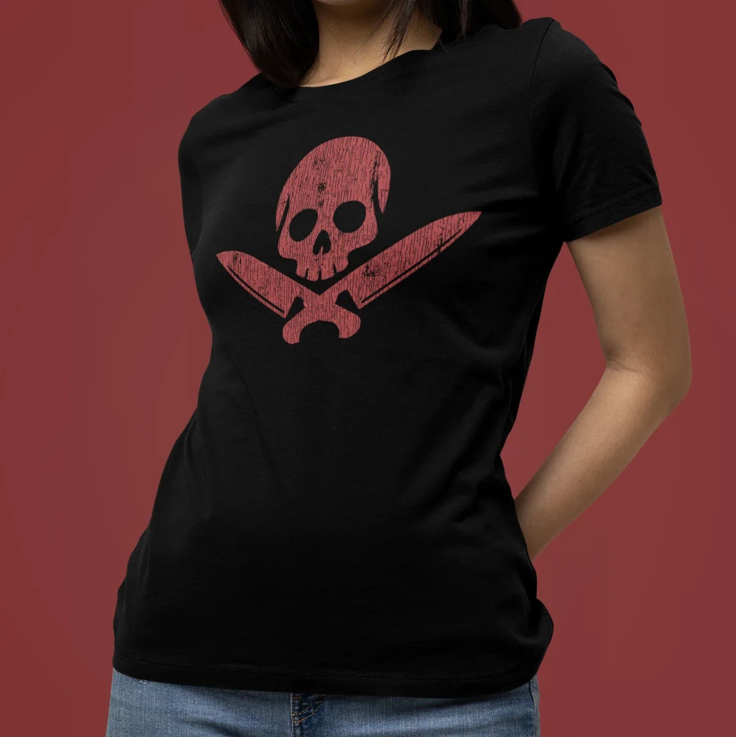 Person wearing a black t-shirt with a red skull and crossbones design on a red background