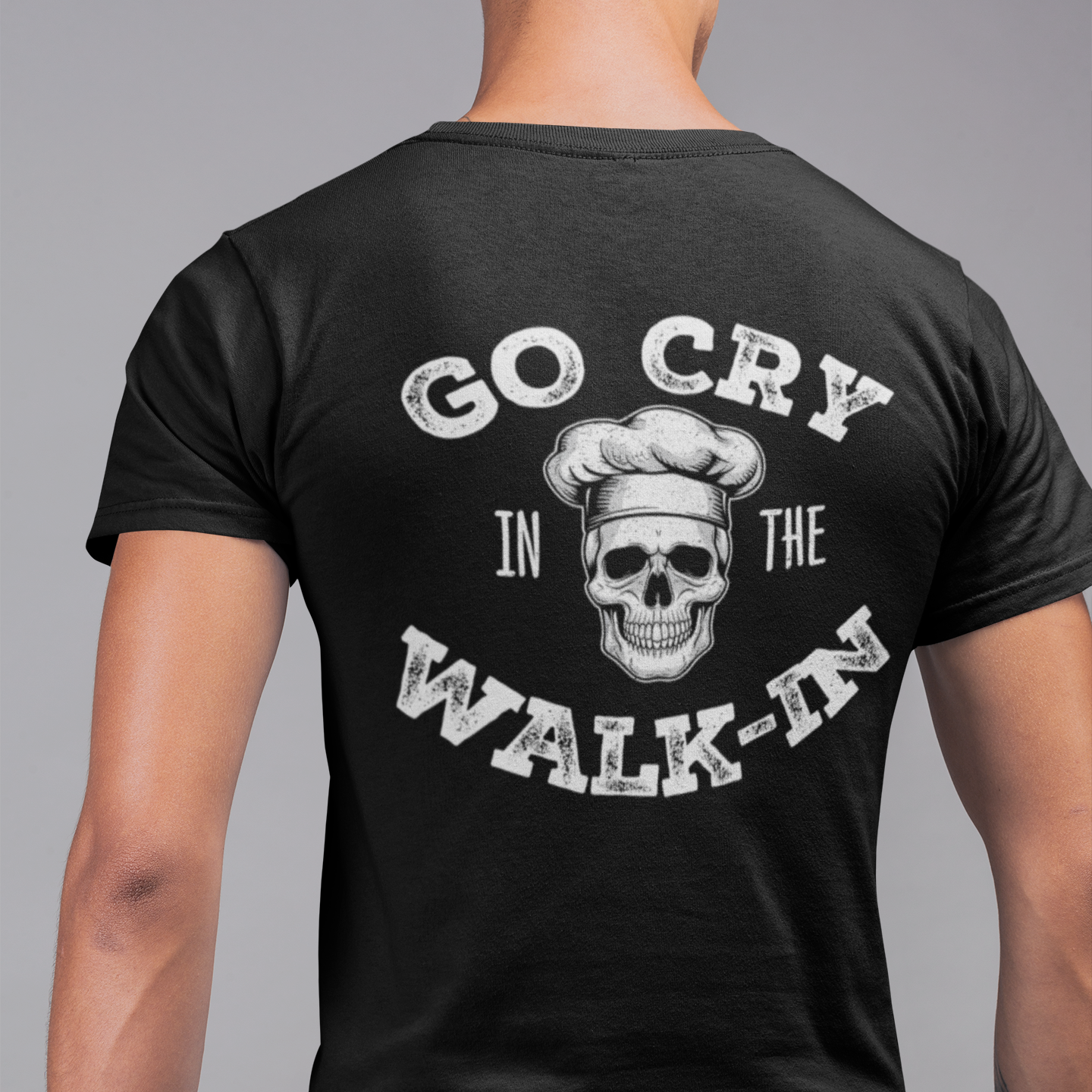 Black t-shirt with skull graphic and text worn by a person on a gray background