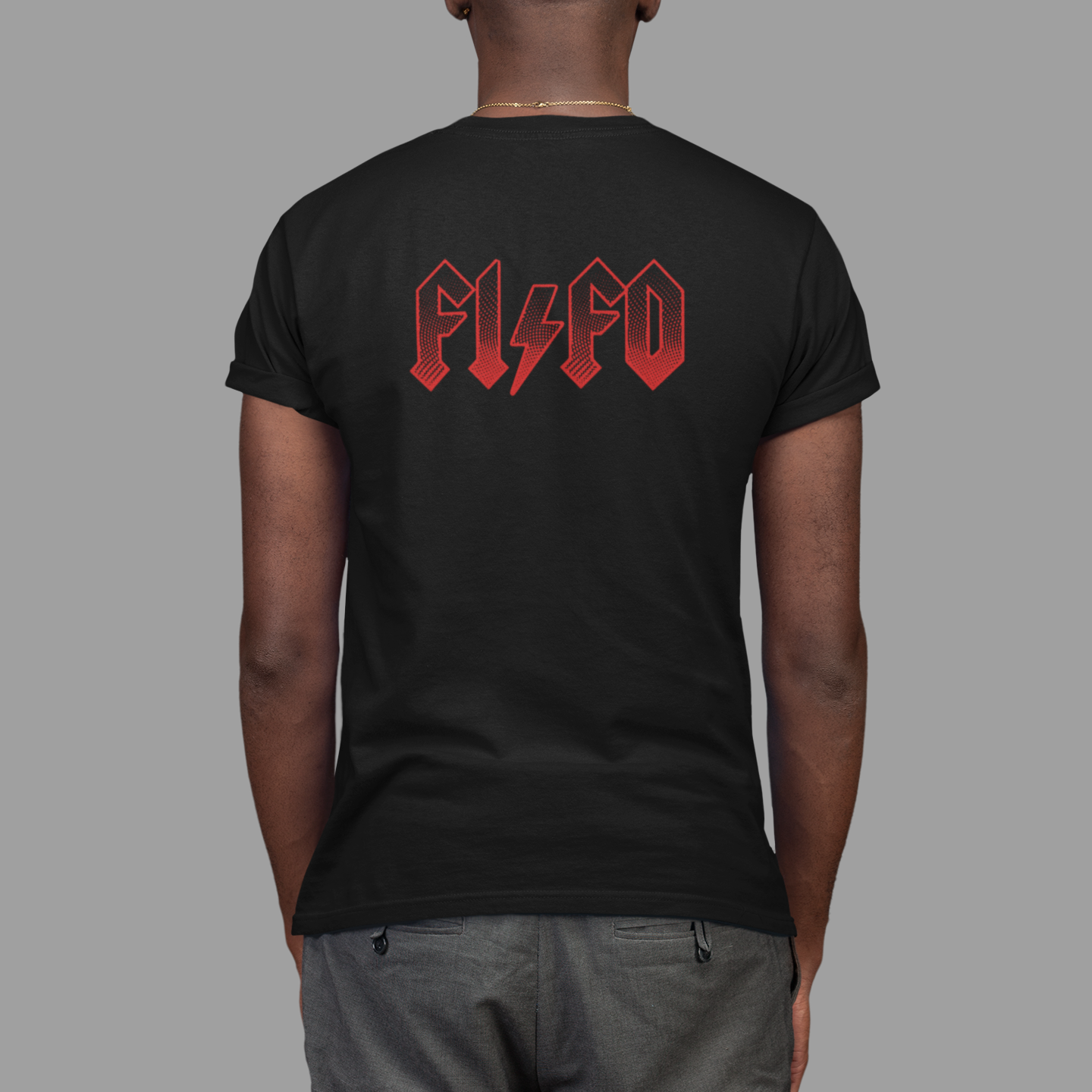 A man viewed from behind wearing a black t-shirt with a red 'FISCO' band logo printed across the upper back, paired with gray pants, against a solid gray background.
