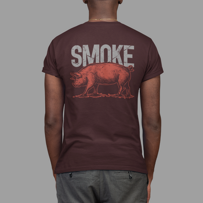 A man viewed from behind wearing a dark maroon t-shirt with a graphic print of a smoking pig and the word 'SMOKE' in distressed white letters, paired with gray pants against a solid gray background.