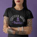 Person wearing a black t-shirt with 'Certified Baking Baddie' text and skull design on a purple background