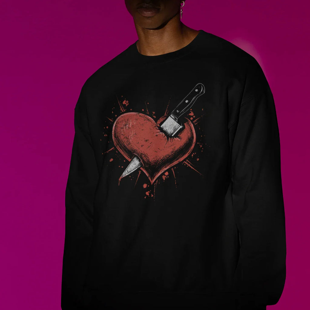 Person wearing a black sweatshirt with a graphic design on a pink background