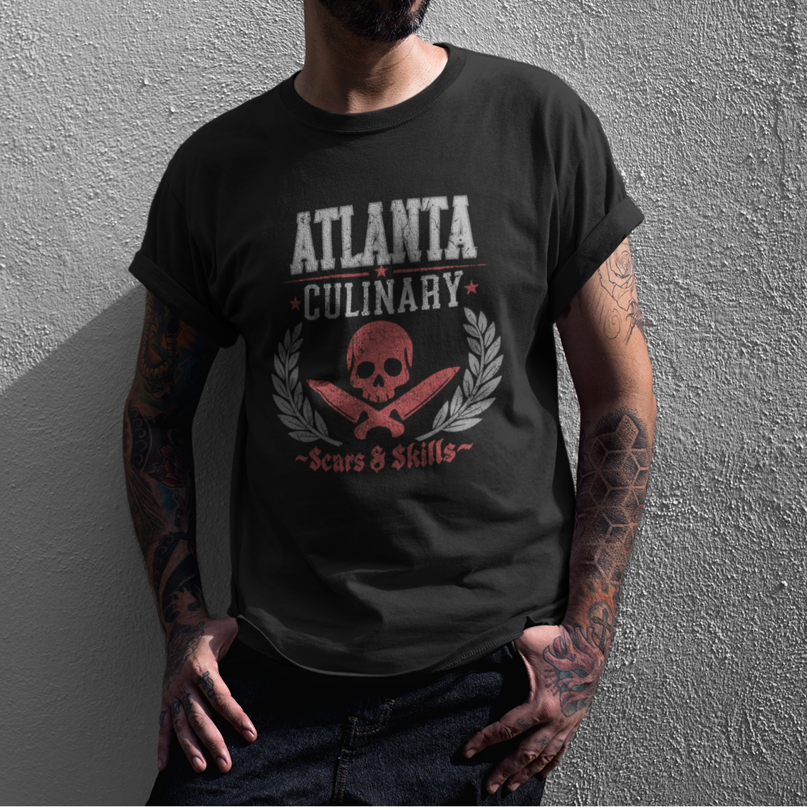 Man wearing a black t-shirt with 'Atlanta Culinary' design against a gray wall