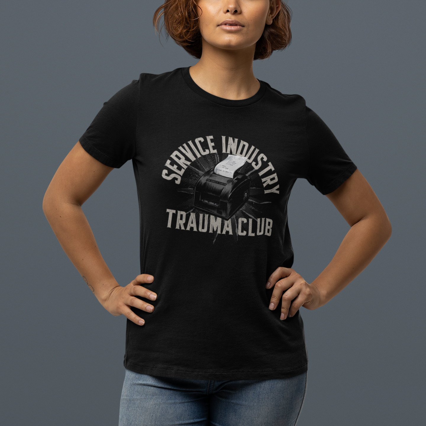 Person wearing a black t-shirt with 'Service Industry Trauma Club' text and graphic on a gray background