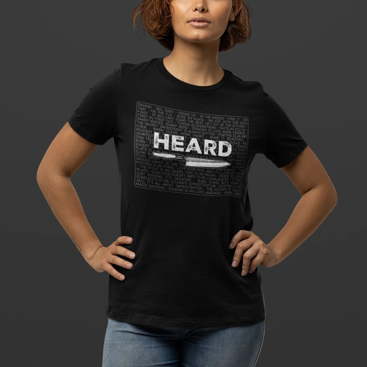 Person wearing a black t-shirt with 'HEARD' graphic design on a dark background