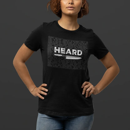 Person wearing a black t-shirt with 'HEARD' graphic design on a dark background