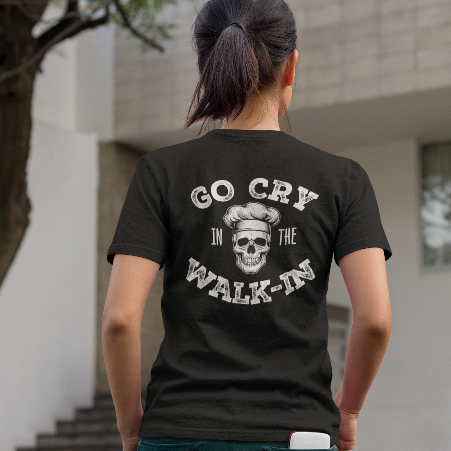 Person wearing a black t-shirt with a graphic design and text, standing outdoors.