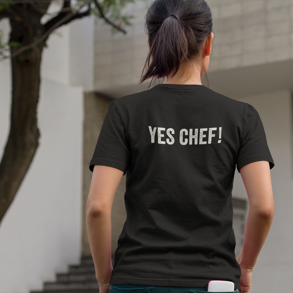 Person wearing a black t-shirt with 'YES CHEF!' text outdoors.