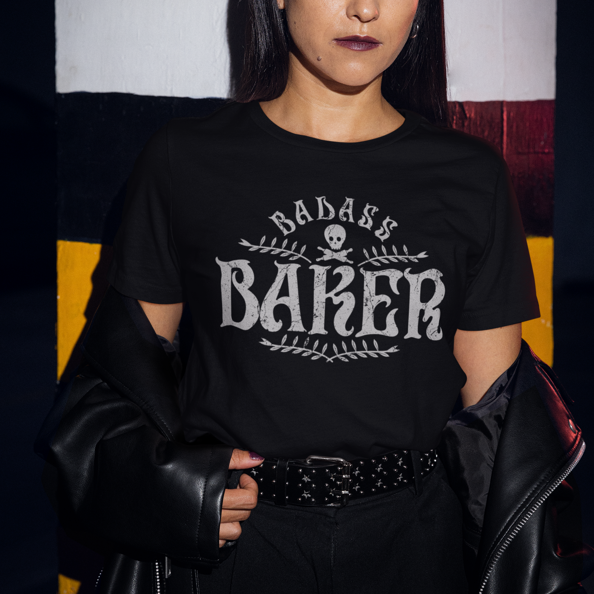 Person wearing a black t-shirt with 'Badass Baker' text, standing against a colorful abstract background.