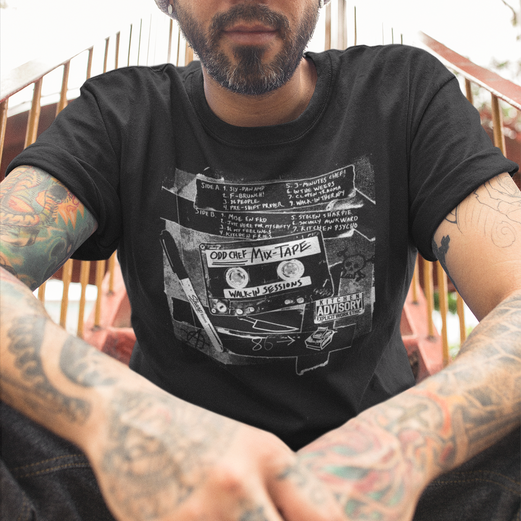 Man wearing a black t-shirt with 'New Jersey Culinary' design, sitting outdoors.