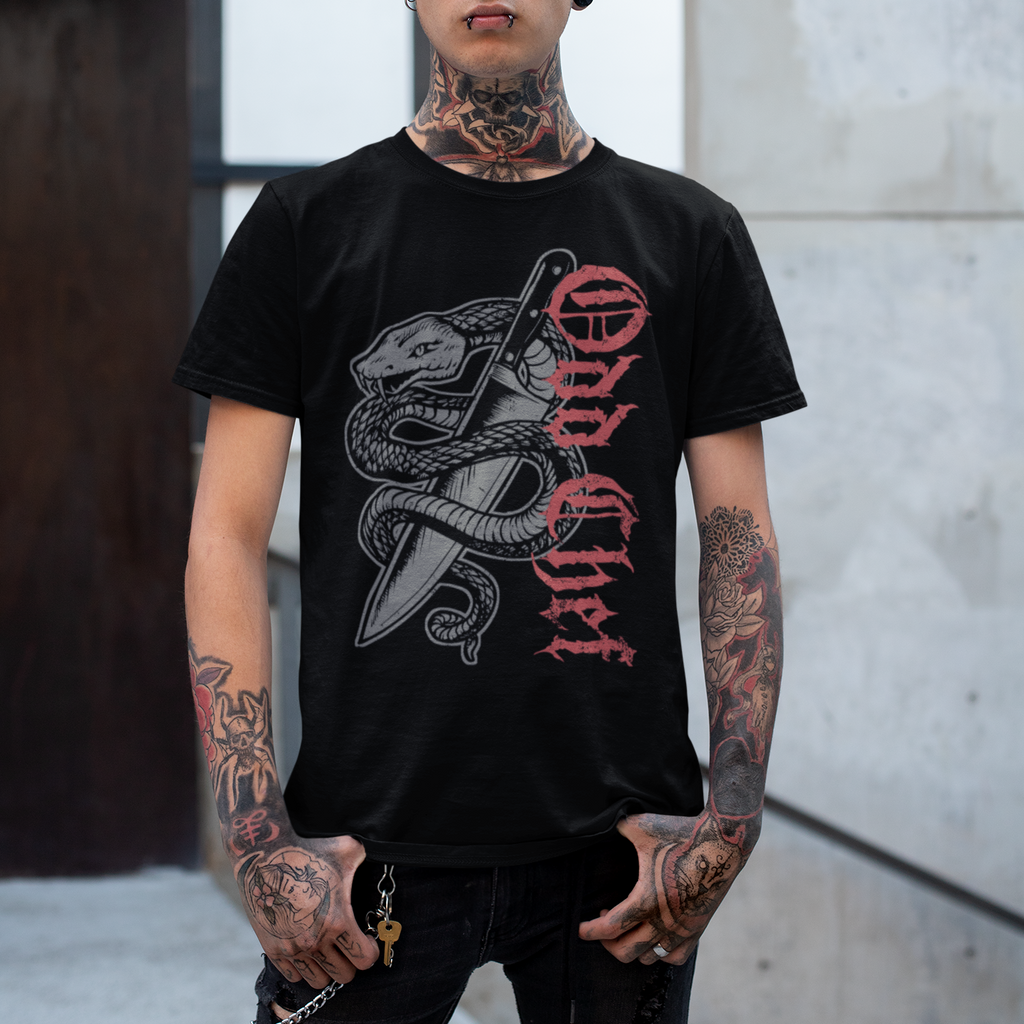 Person wearing a black t-shirt with a graphic design, standing against a concrete wall.