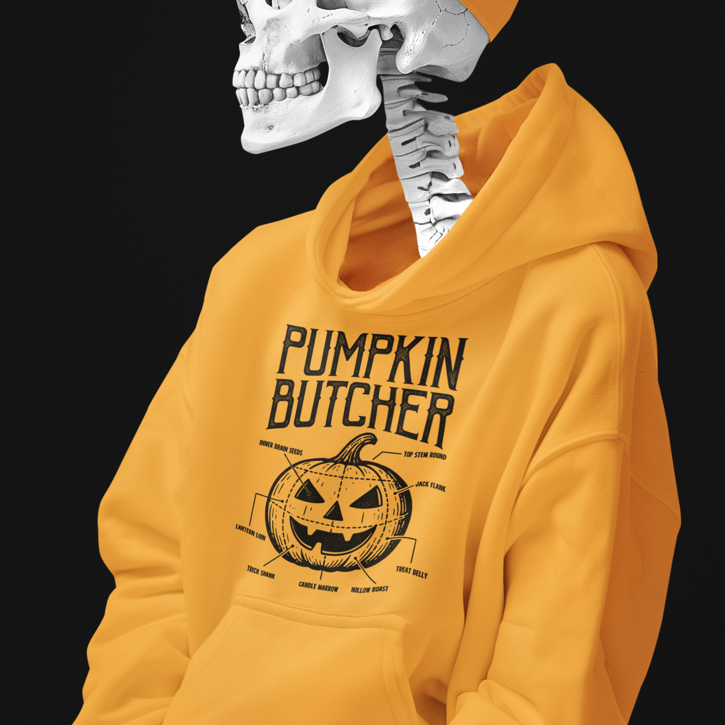 A yellow hoodie with a black graphic print reading 'PUMPKIN BUTCHER' and a pumpkin illustration, worn by a skeleton mannequin with a matching yellow cap against a black background.