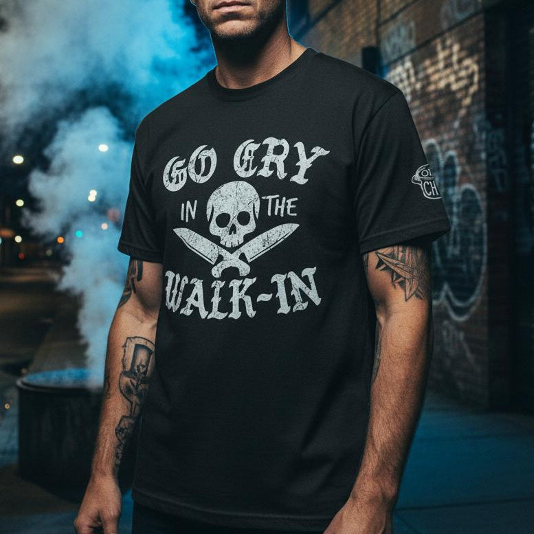 Man wearing a black t-shirt with text and skull design on a street at night.
