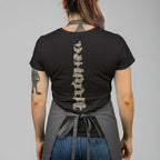 Person wearing a black t-shirt with a spine design on the back, standing against a gray background.