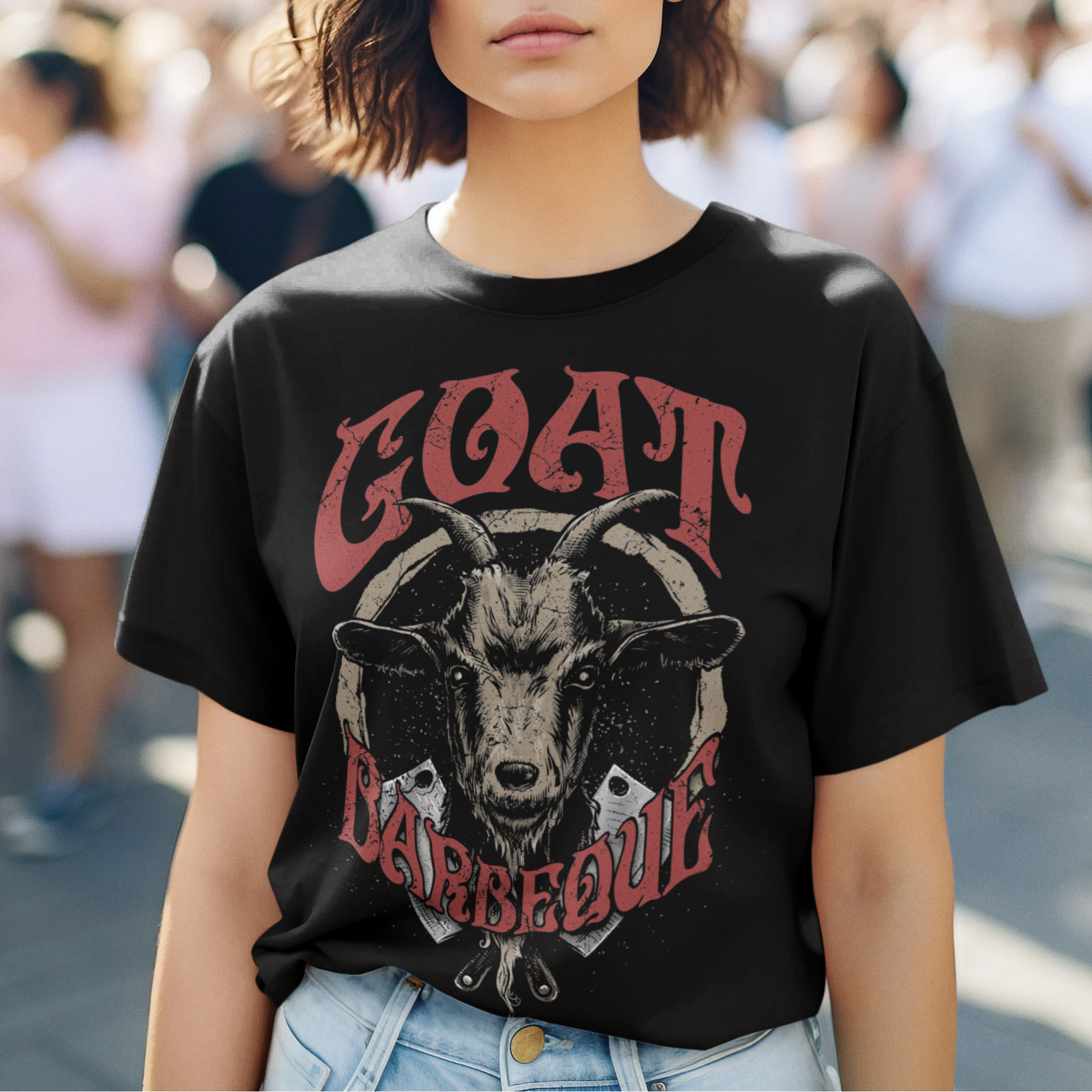 Woman wearing a black t-shirt with a graphic design of a goat and text, standing outdoors.