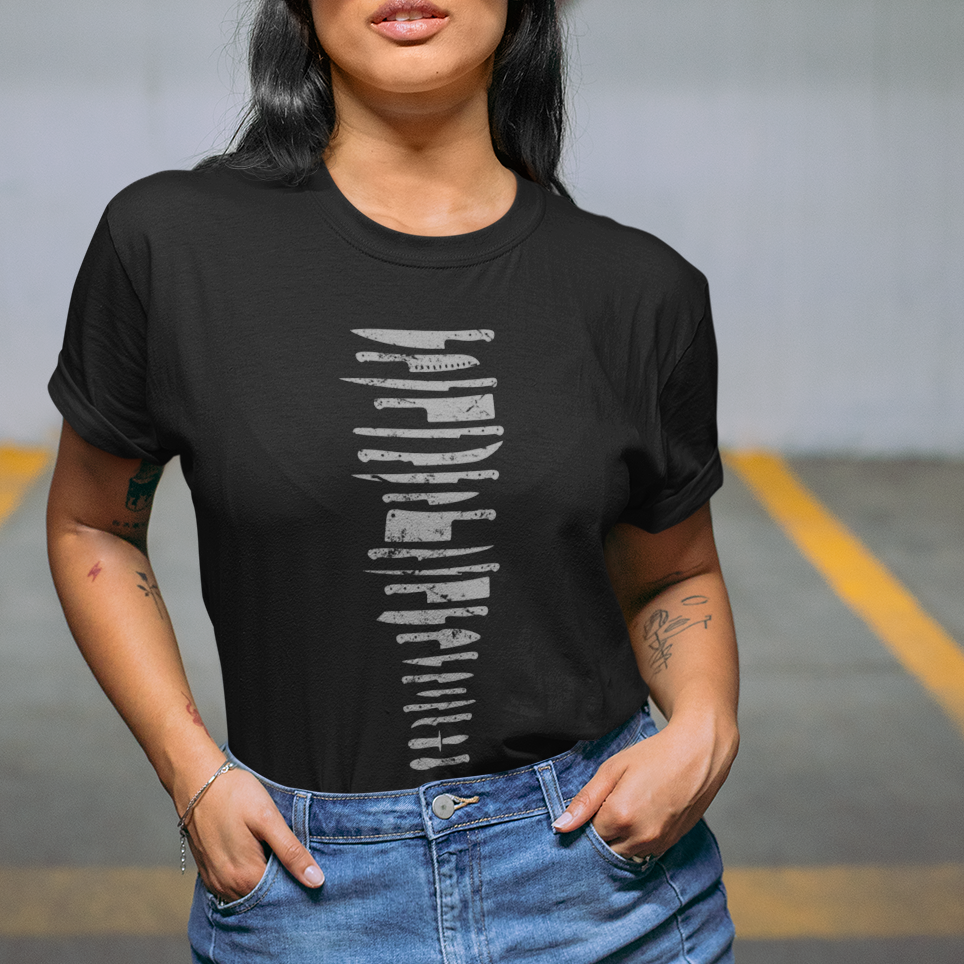 A woman posing in a parking garage wearing a black t-shirt with a white graphic print, a denim mini skirt, and a white baseball cap with blue text.