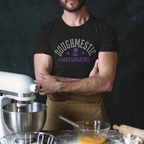 Man in a black t-shirt with 'Doughestic' text standing in front of baking equipment.