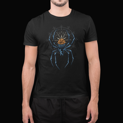 A man wearing a black short-sleeve t-shirt with a detailed graphic of a blue spider holding a gold orb, set against a dark background.