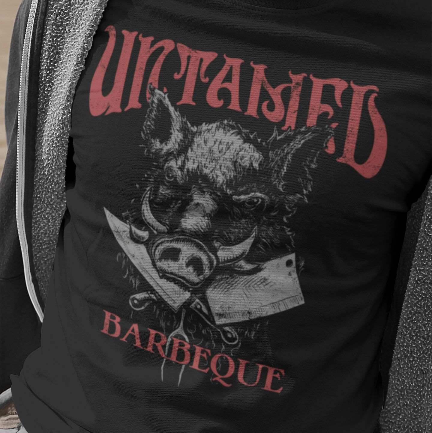 Person wearing a black t-shirt with a graphic of a pig and text 'Untamed Barbeque'.