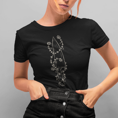A woman with bright orange hair posing in a black short-sleeve t-shirt with a silver graphic print and a matching black denim button-front mini skirt, set against a solid gray studio background.