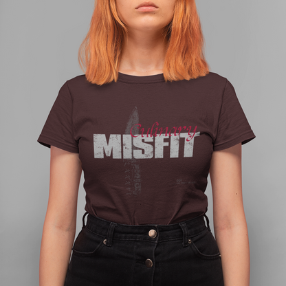A model with bright orange hair wearing a dark brown Misfit band t-shirt and black high-waisted jeans, standing against a solid gray background.