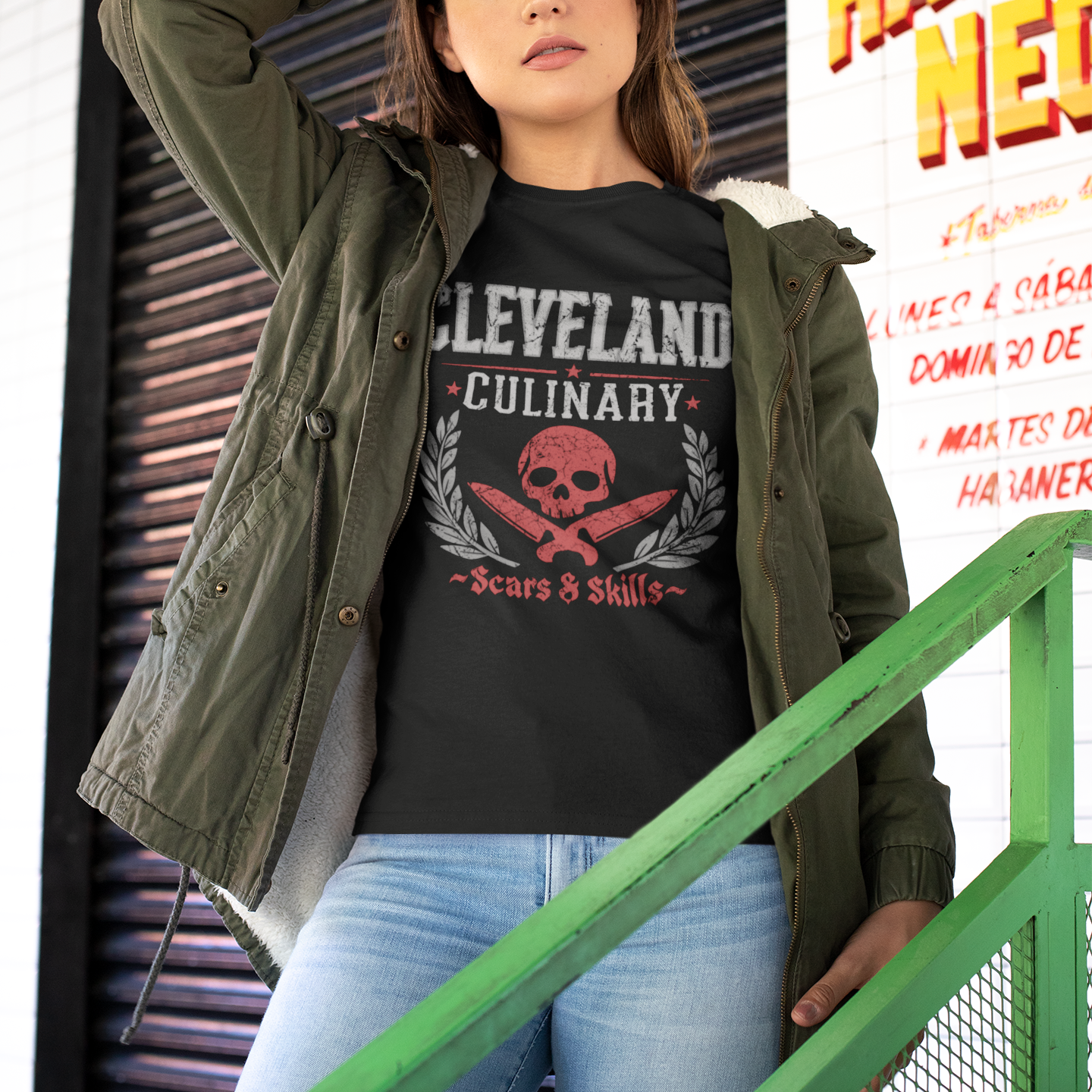 Woman wearing a black 'Cleveland Culinary' t-shirt with a skull design, standing in front of a building with a Habanero Neon sign.