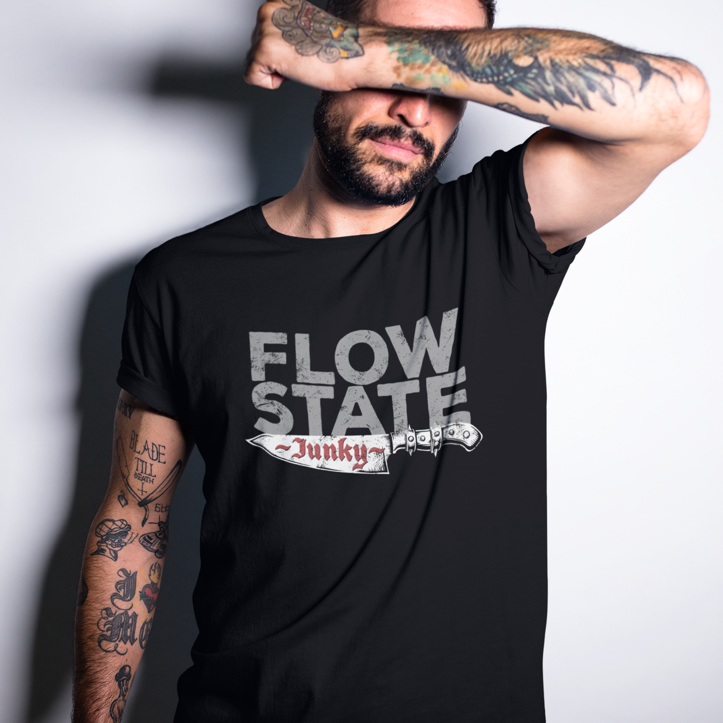 Man wearing a black t-shirt with 'Flow State Junky' text, covering his face with his arm.