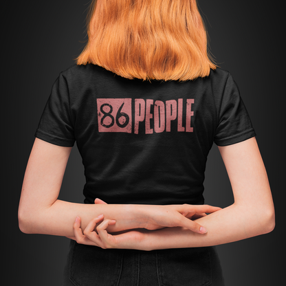 A person viewed from behind wearing a black short-sleeve T-shirt with a pink graphic reading '86 PEOPLE' across the upper back, against a dark studio background.