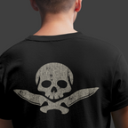 Person wearing a black t-shirt with a skull and crossbones design on the back against a dark background