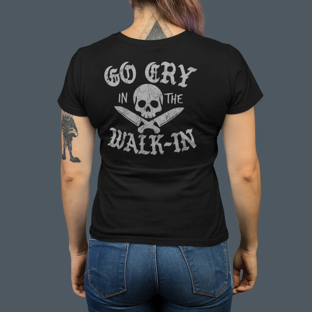 Person wearing a black t-shirt with text and skull design on the back, standing against a dark background.